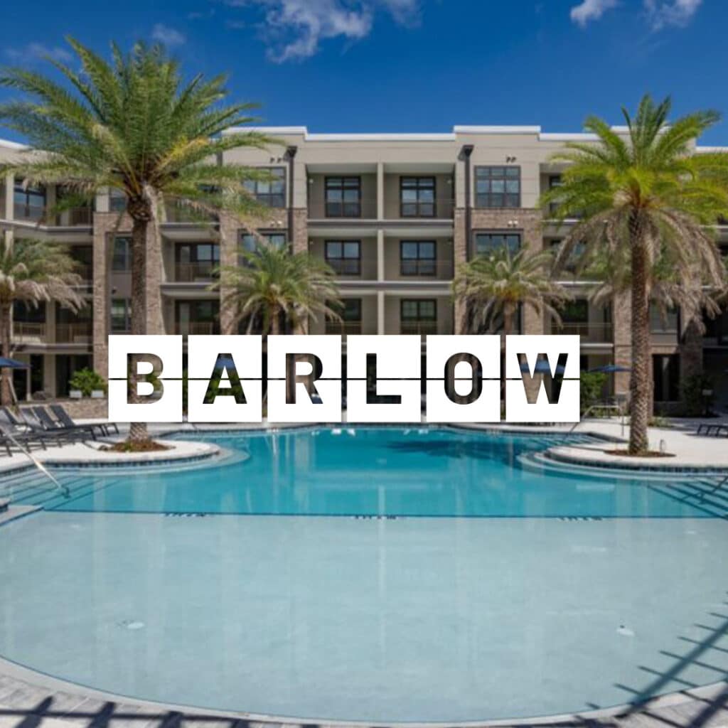 Modern apartment building with a large swimming pool in front and palm trees lining the area. The word "Barlow" is displayed prominently across the center.